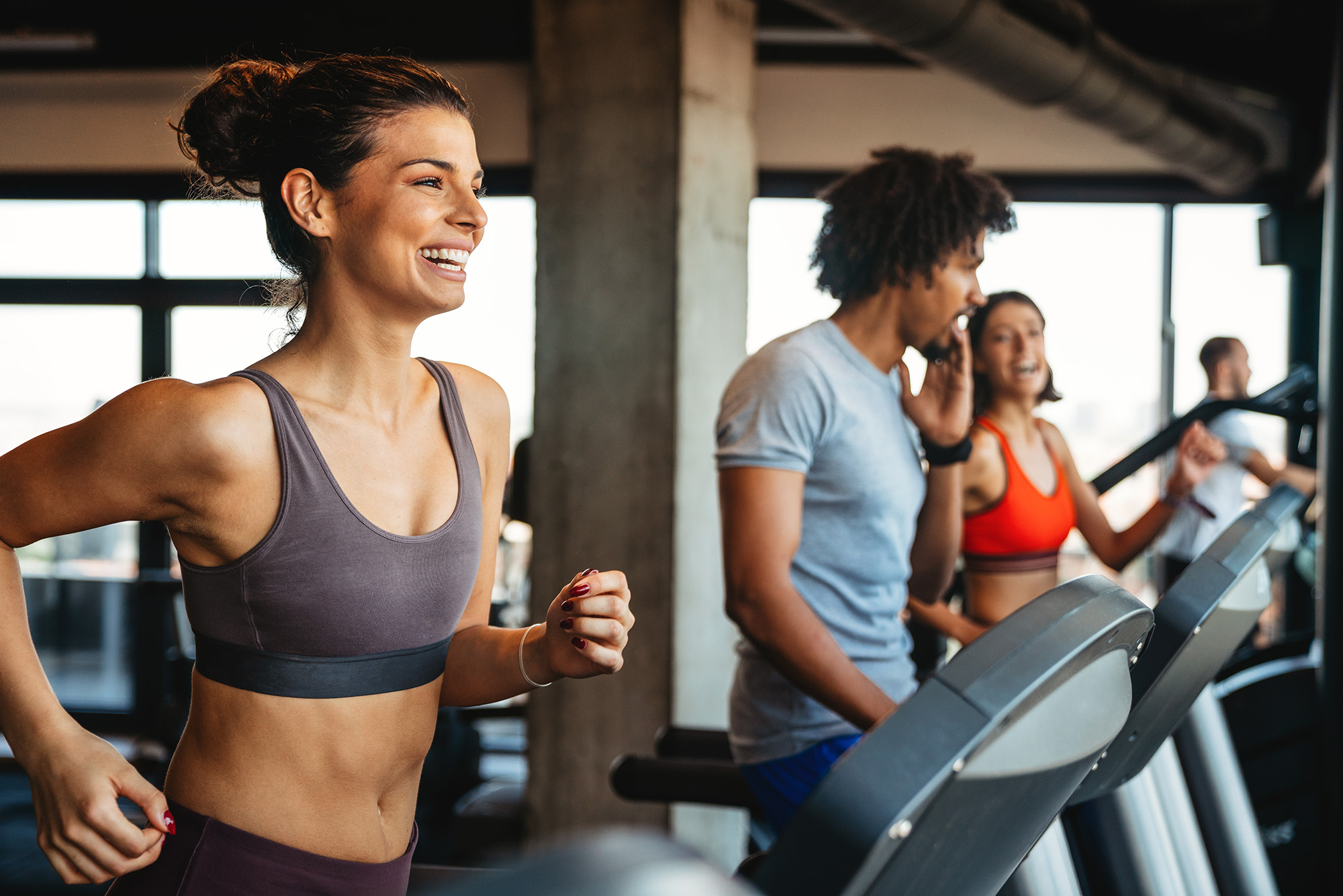 Gym members smiling on treadmills